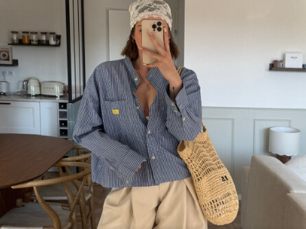 Manon en miroir-selfie, chemise rayée et sac en filet, dans une cuisine lumineuse